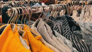 大量的多色暖冬毛衣挂在购物中心商店的衣架上，买家路过。